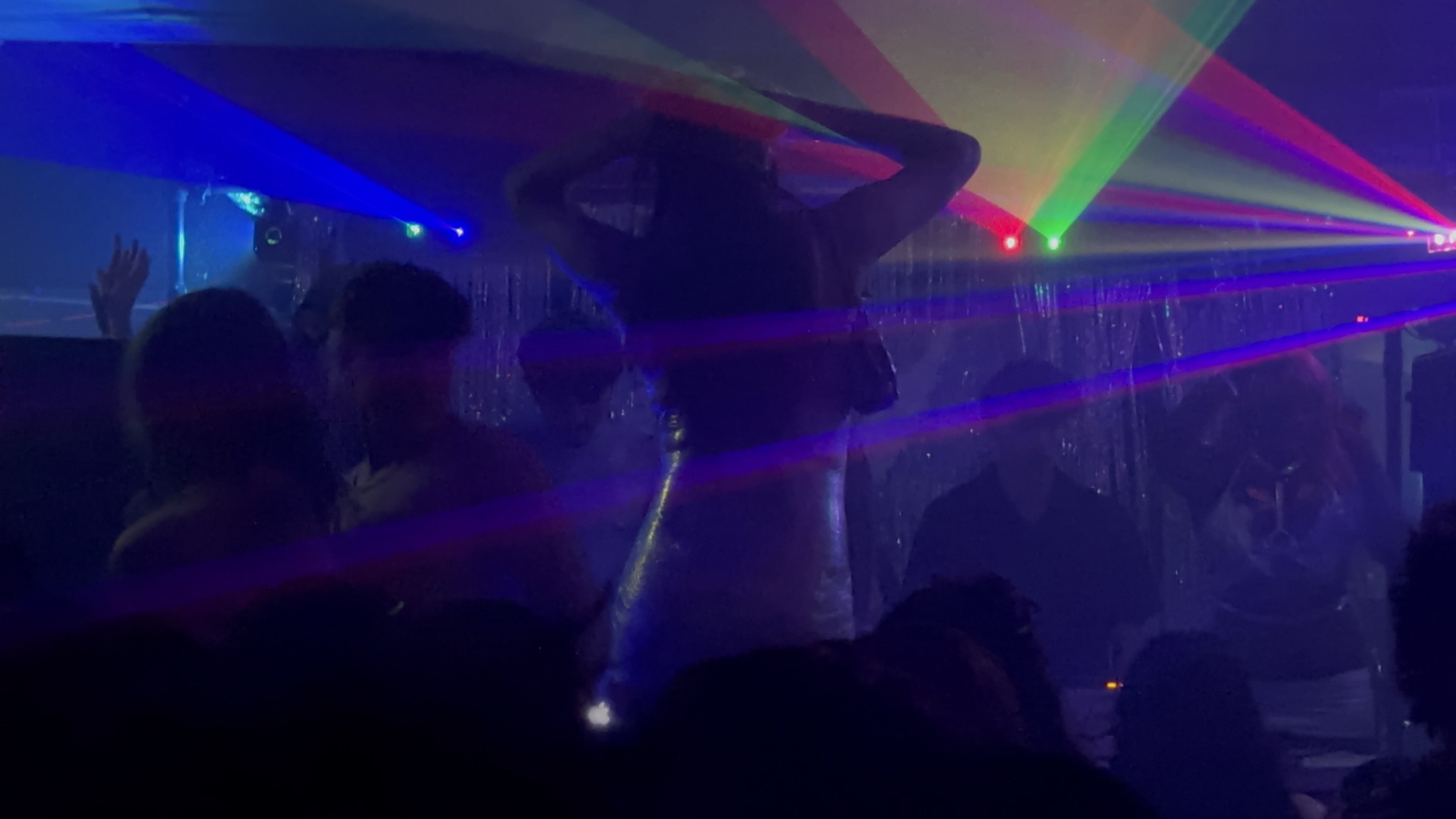 The crowd under rainbow lasers at a USO set