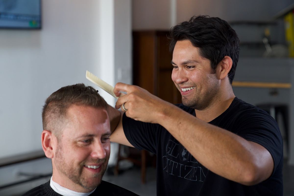 A barber combing out a happy client