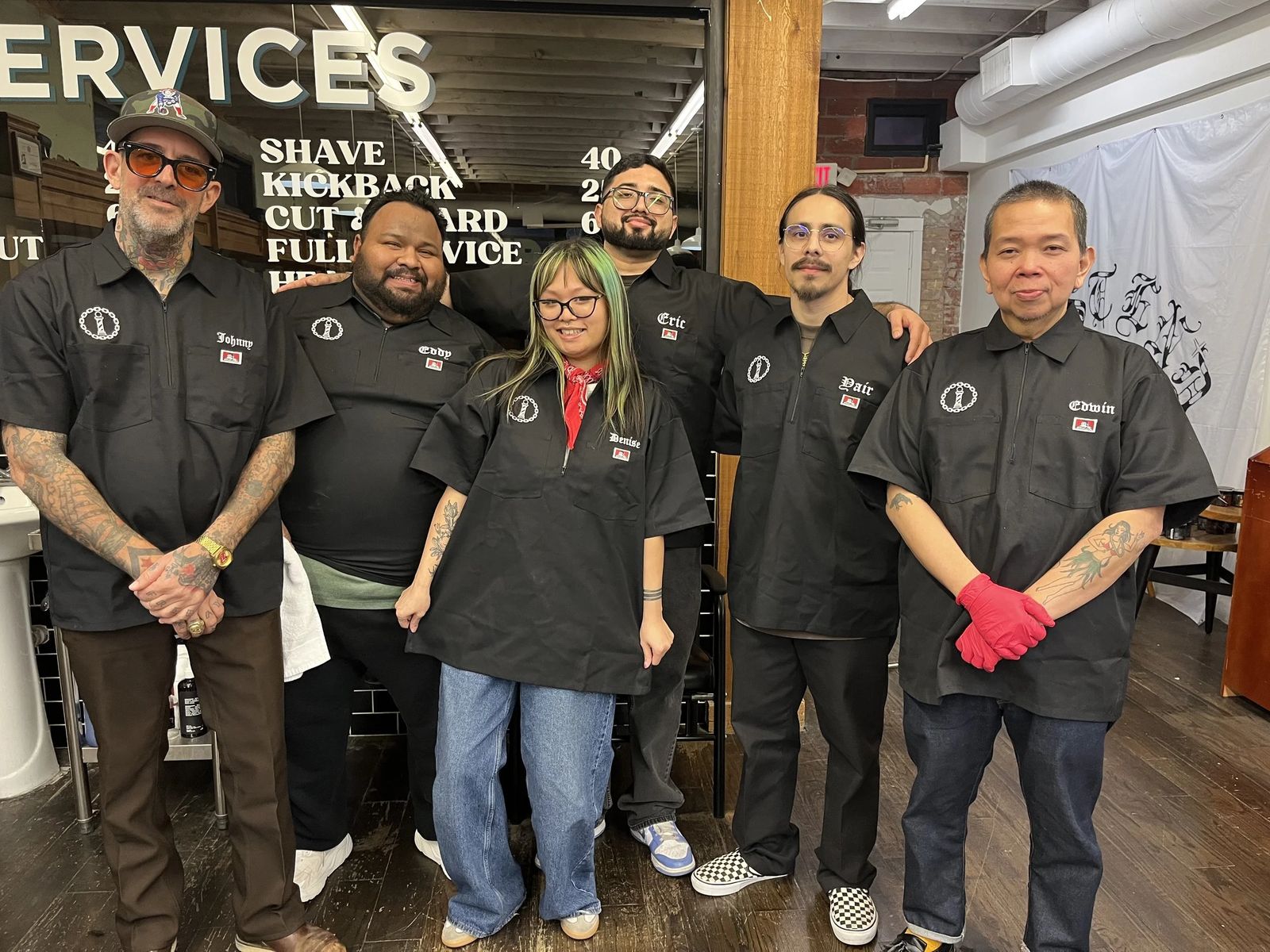 The East End Barber crew in front of the services wall