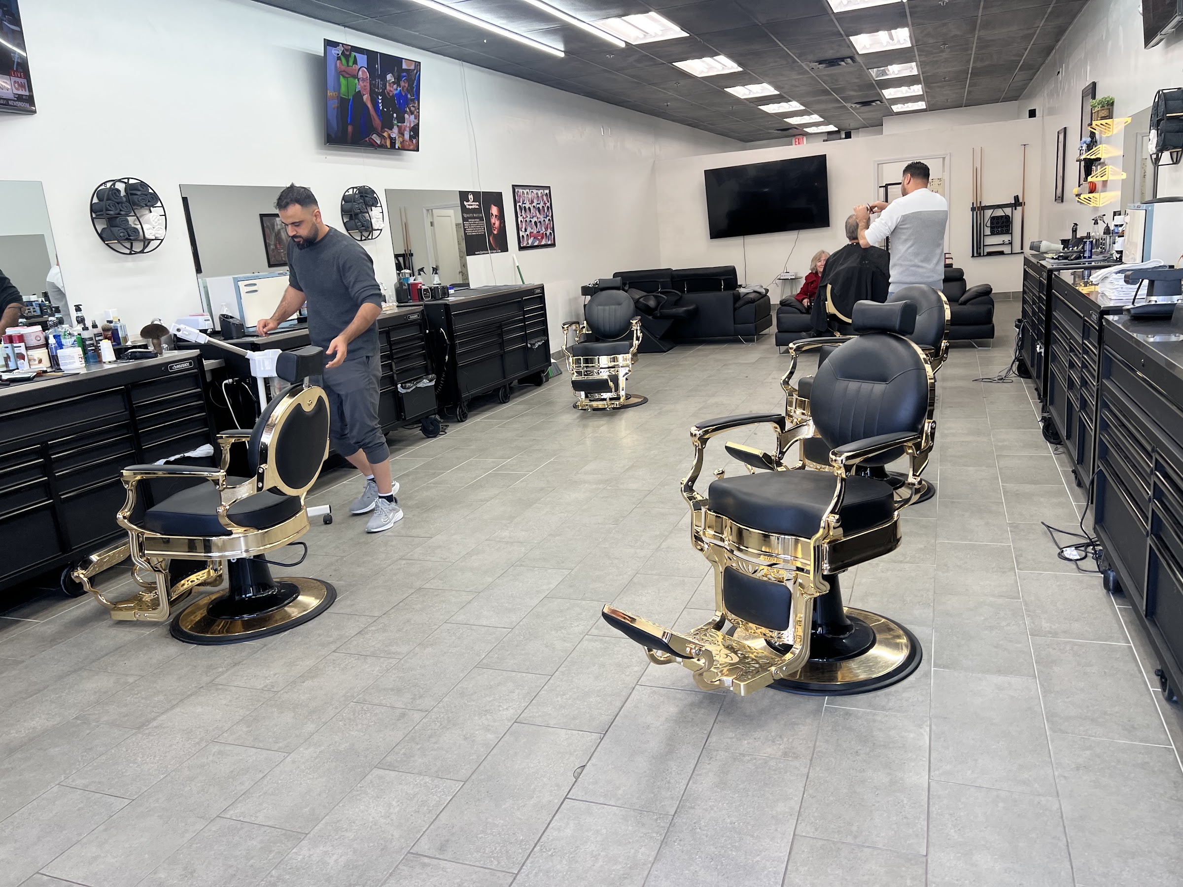 Inside Kingsman Barbershop: black and gold antique barber chairs down a long, bright shop floor