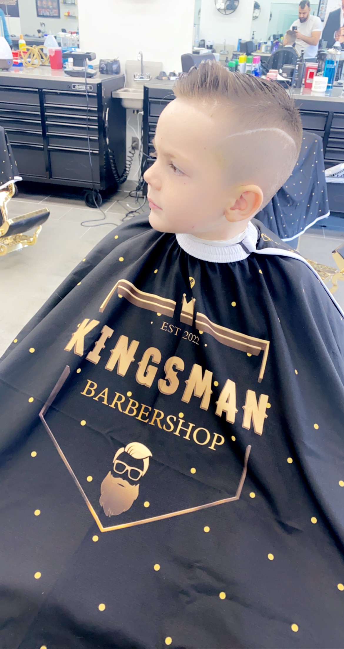 Kids cut with a hard part, in the Kingsman cape