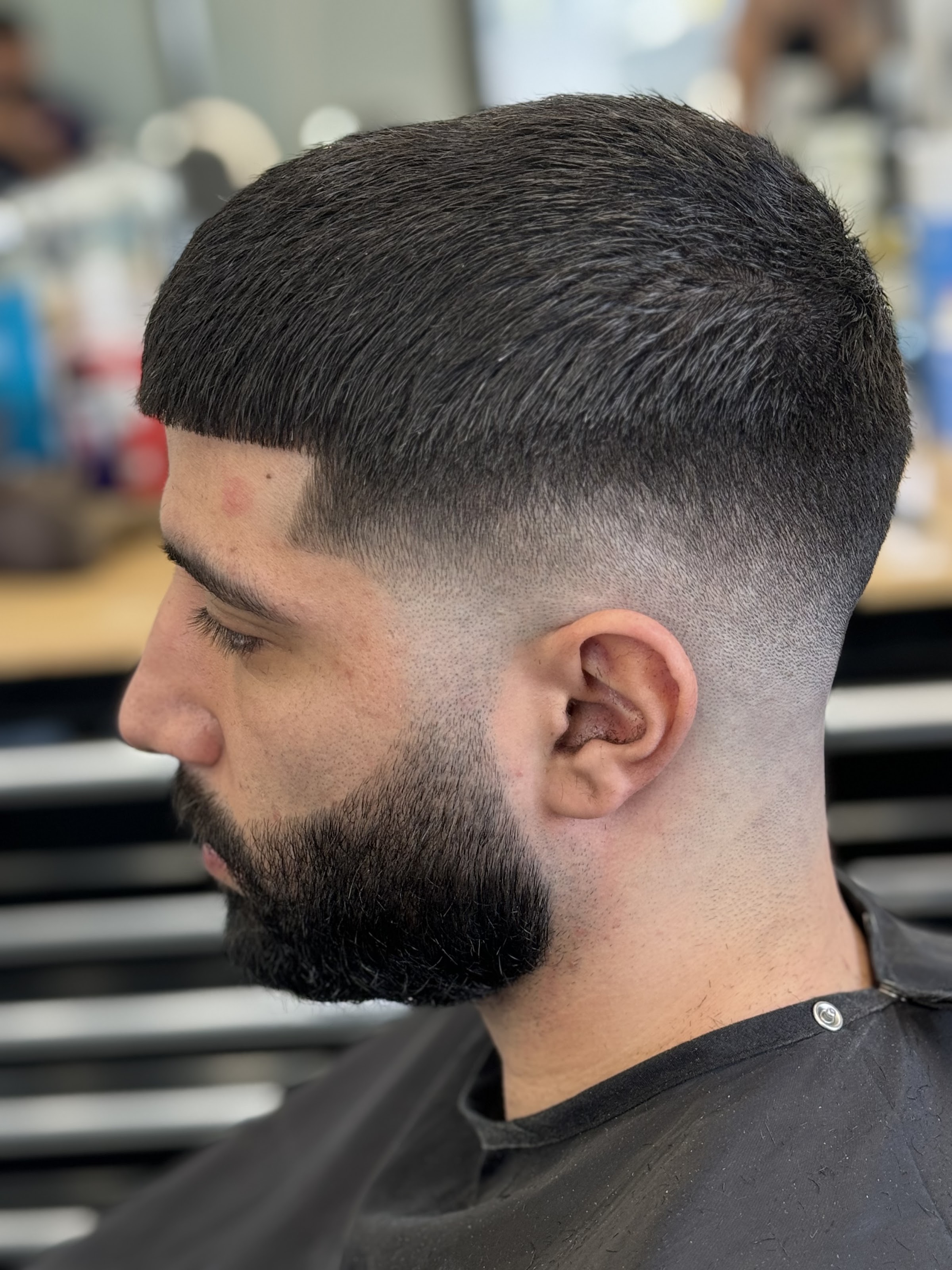Crisp mid fade with a sharp lineup and full sculpted beard