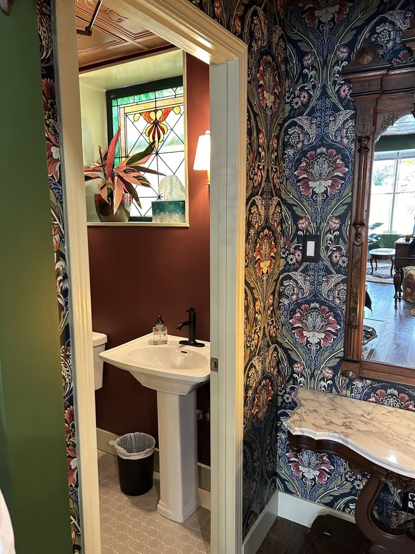 The wallpapered wash room with stained glass
