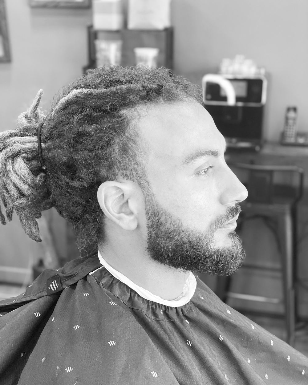 Dreads tied up with a sculpted beard, in black and white